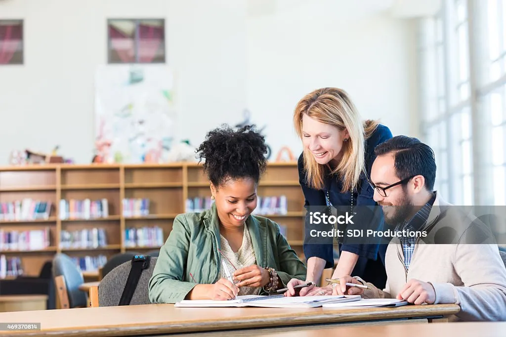 Two adults talking to a trainer in a classroom.