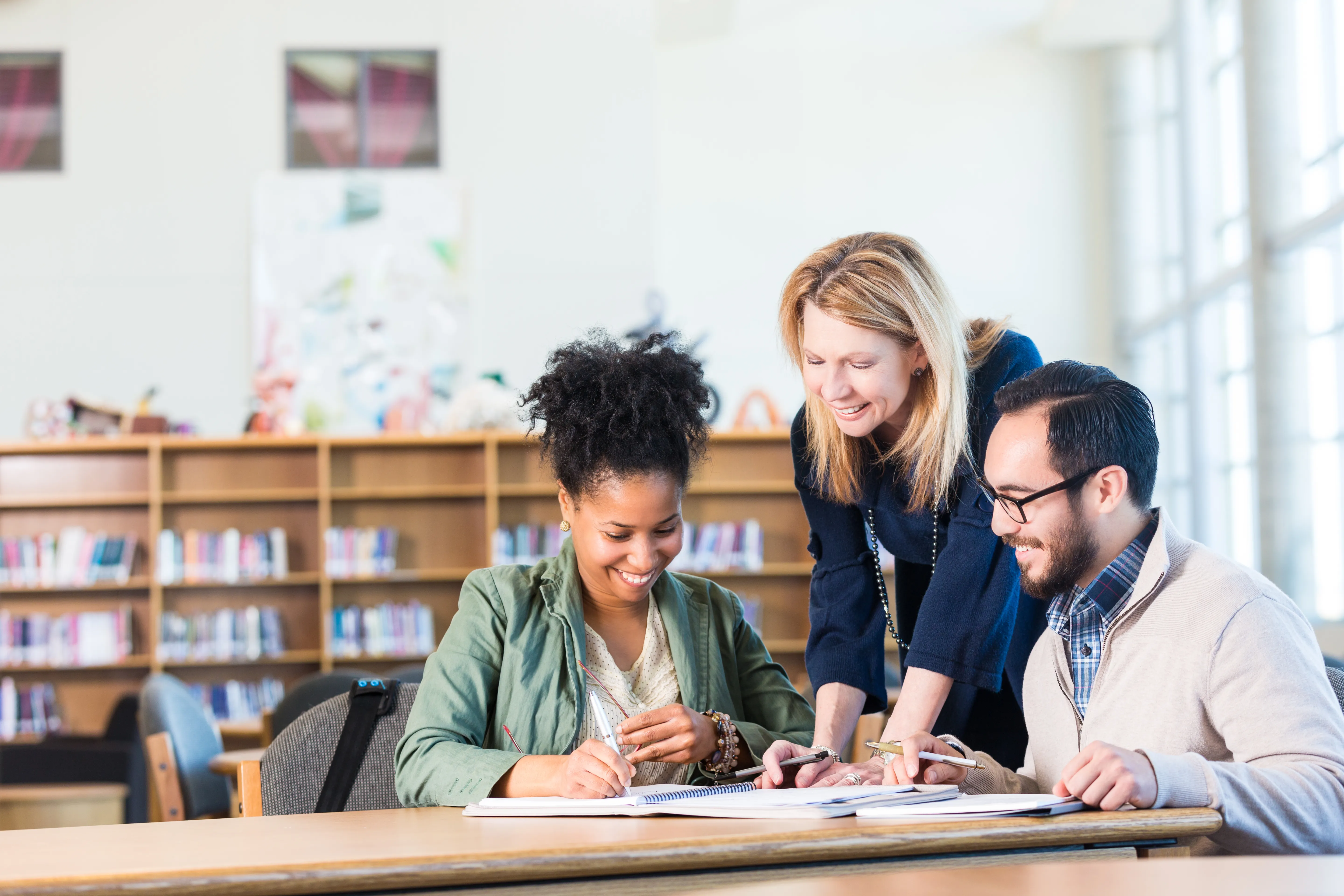 Two adults talking to a trainer in a classroom.